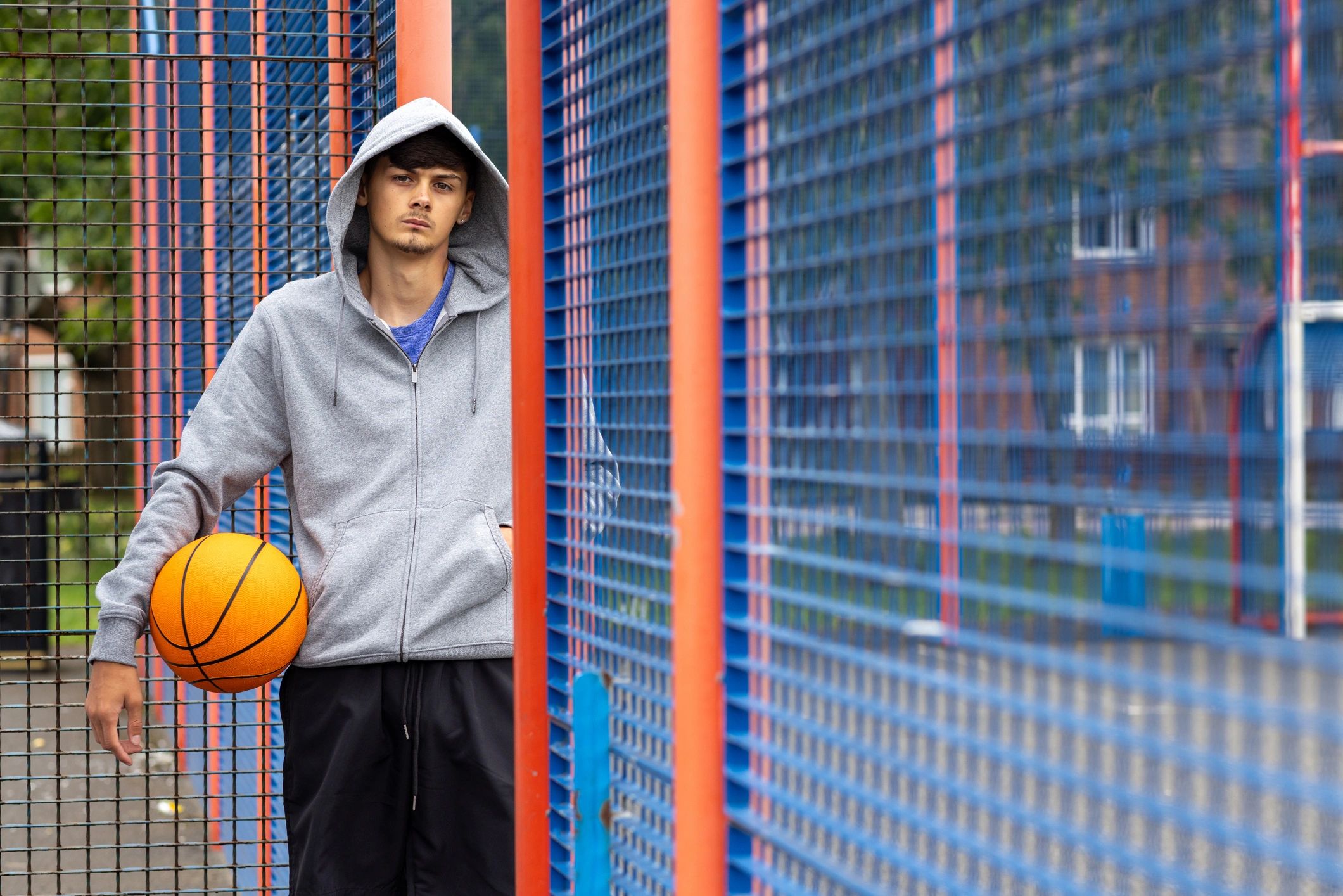 Teen basketball player holding a ball on an outdoor court